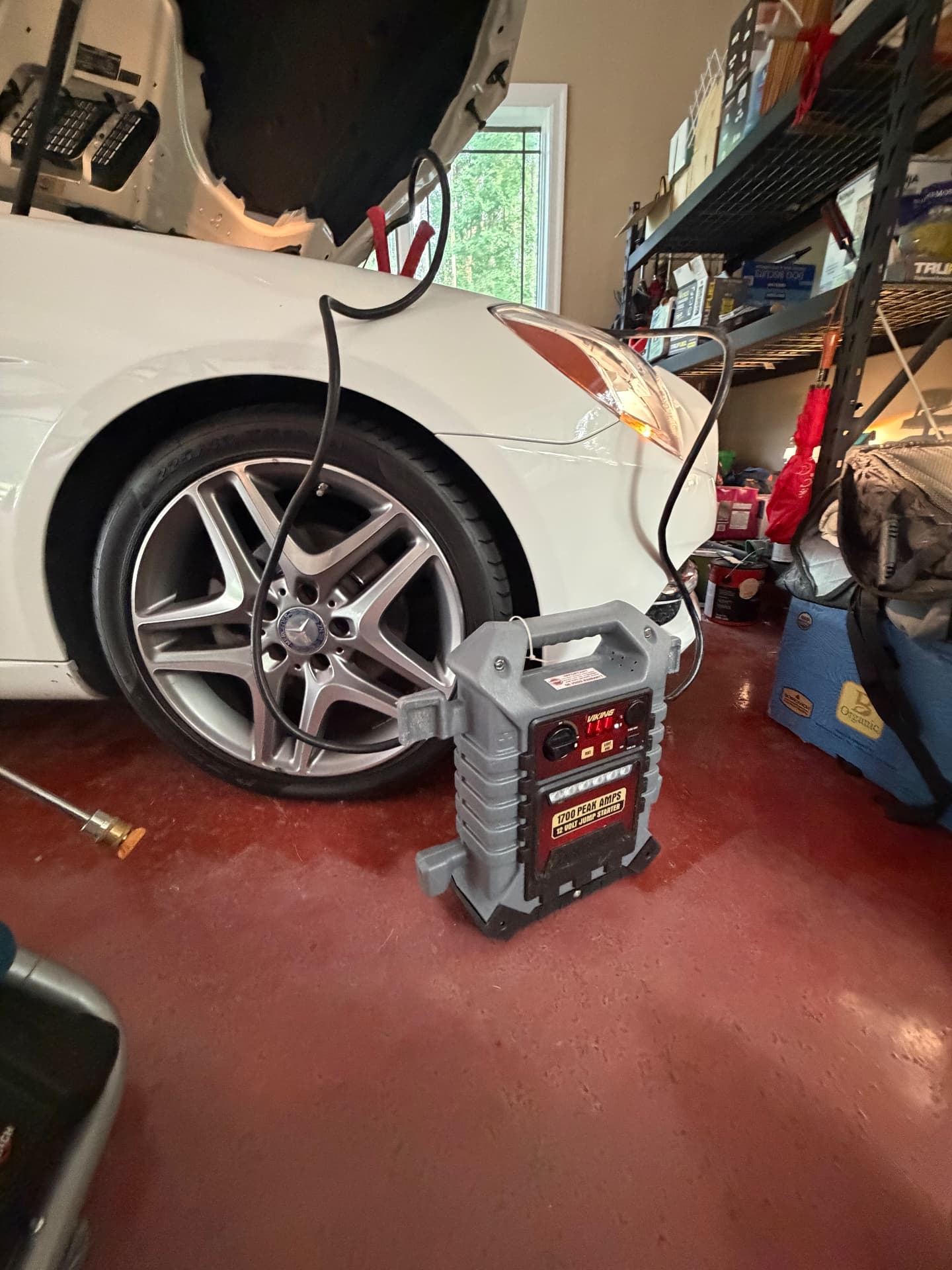 Portable 1700 amp jump starter connected to a Mercedes sedan